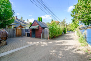 Private gated driveway behind the cottage with a red garage under a striped awning
