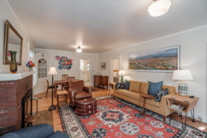 Living room seating with a deep sofa and a leather chair drawn up to the brick fireplace