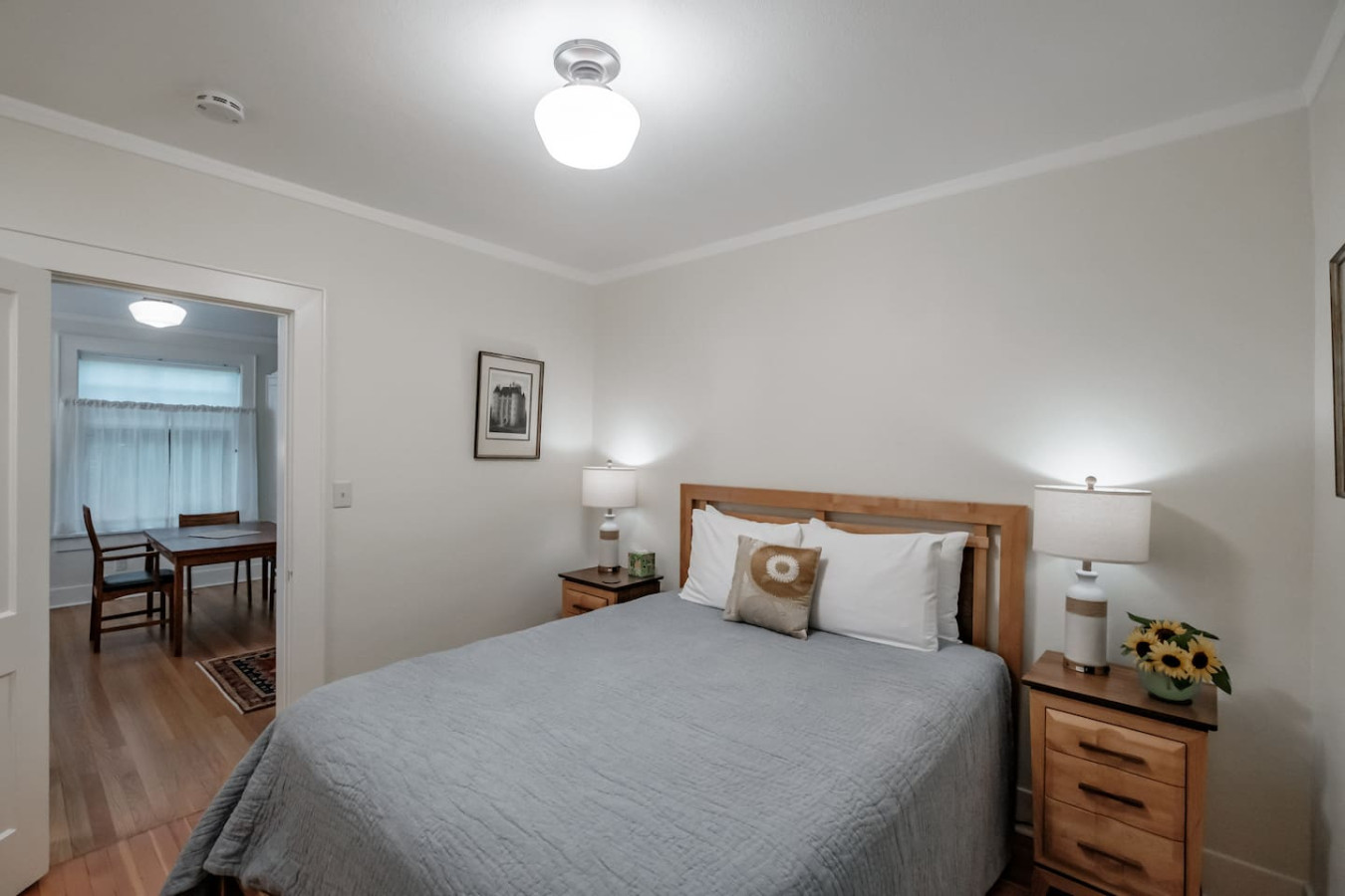 Primary bedroom with a queen bed, a nightstand and lamp on each side, and a doorway through to the sitting area