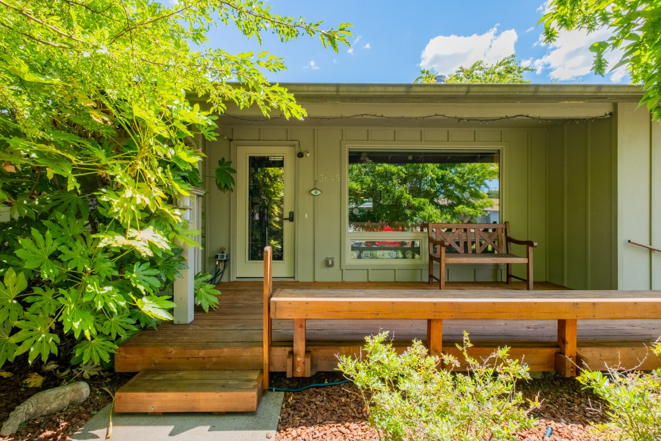 Covered front entry porch with a wood bench at Canterbury Retreat, a furnished home in north Corvallis